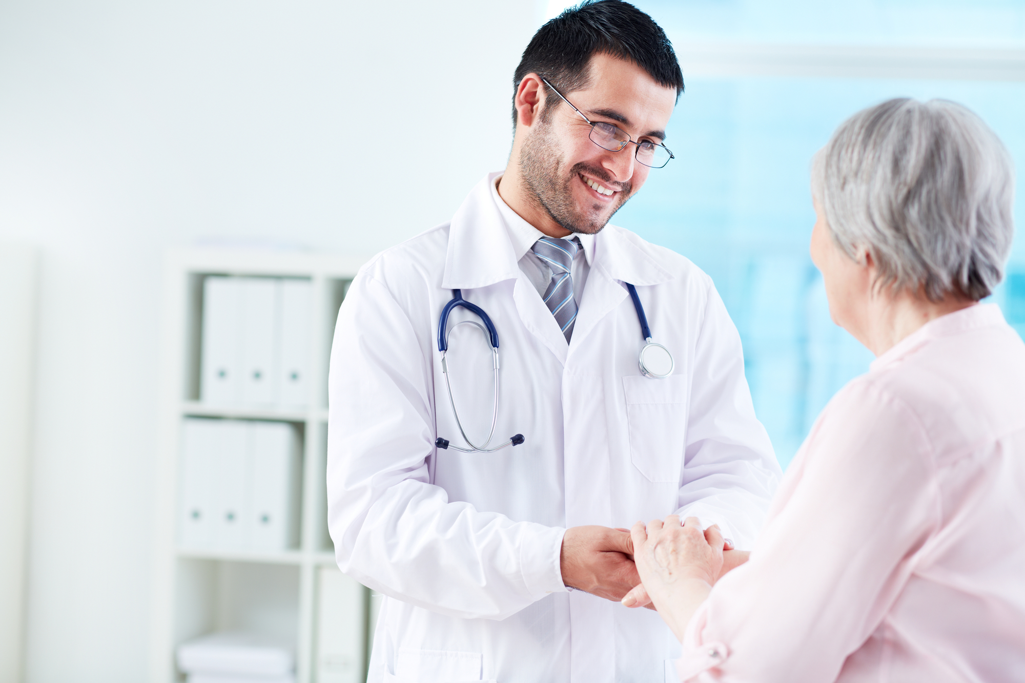 A male doctor shakes hands with an elderly woman