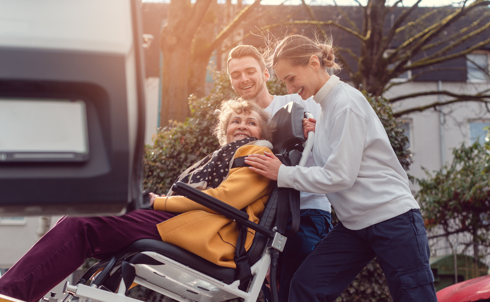 A woman in a wheelchair is being assisted by two individuals