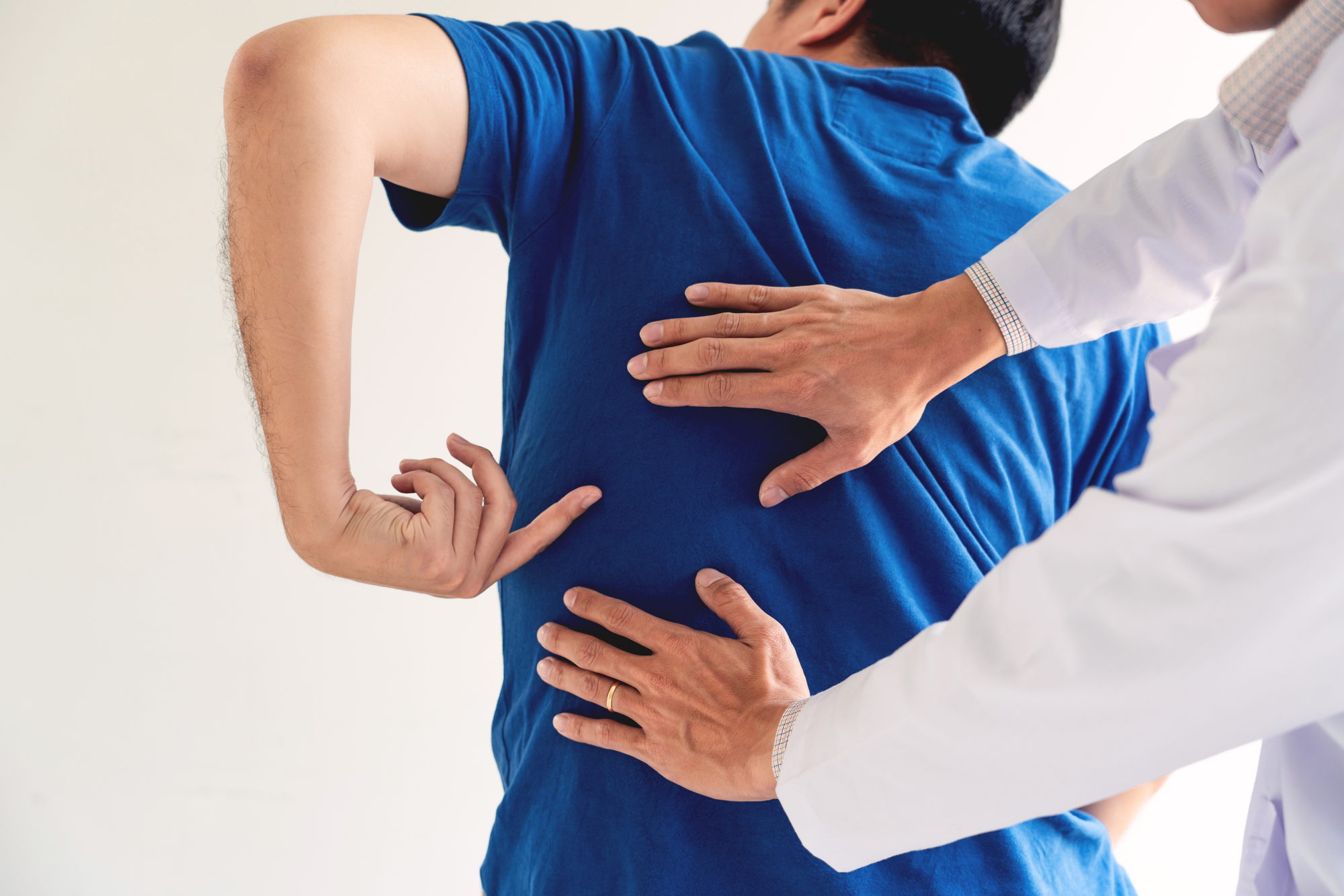 A physician assists a man with back pain